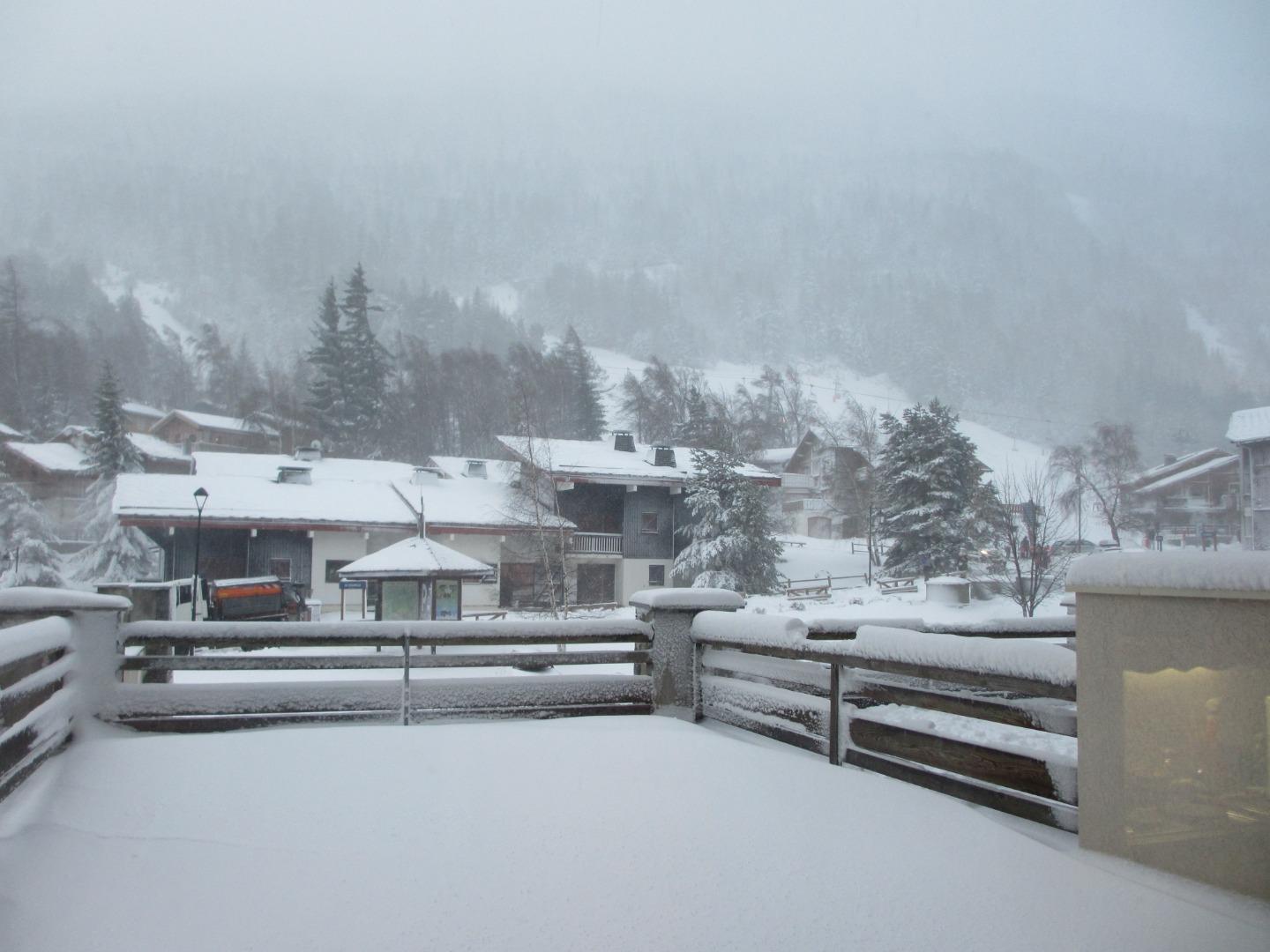 Vue hivernale sur la terrasse avec au fond les pistes de ski