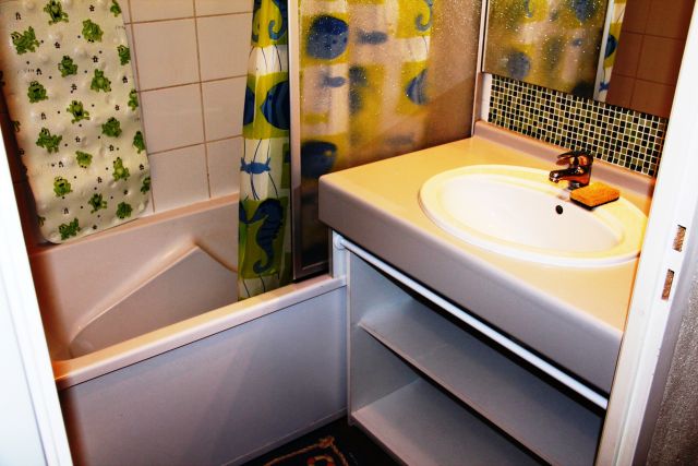 Salle de bain avec pare-douche et rangements.