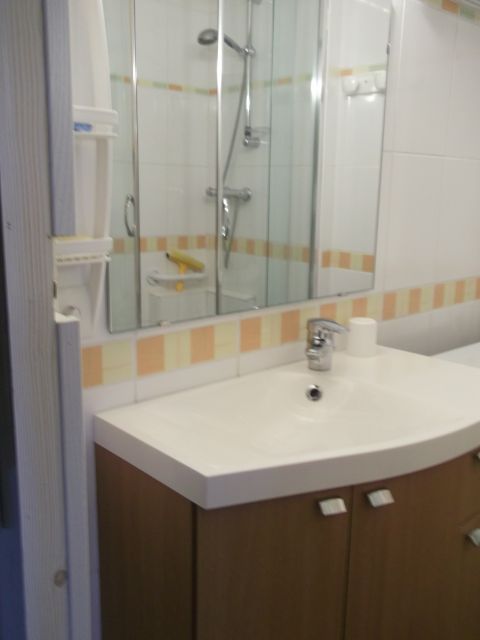 Salle de bain : douche, machine à laver, toilette, sèche cheveux, étendoir à linge mural et rangement.