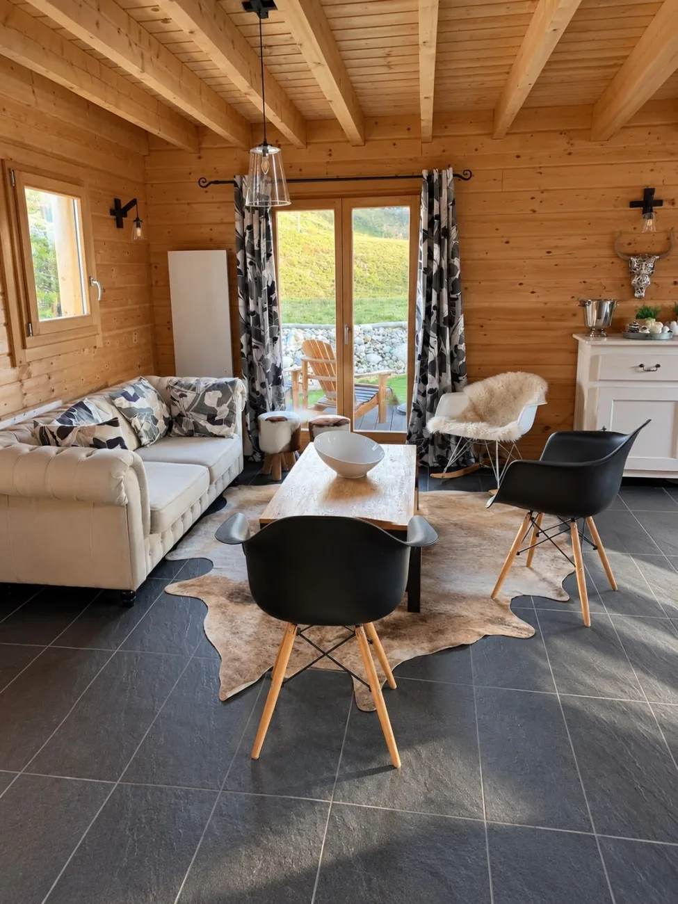 Salon avec canapé chesterfield et baie vitrée donnant sur la terrasse