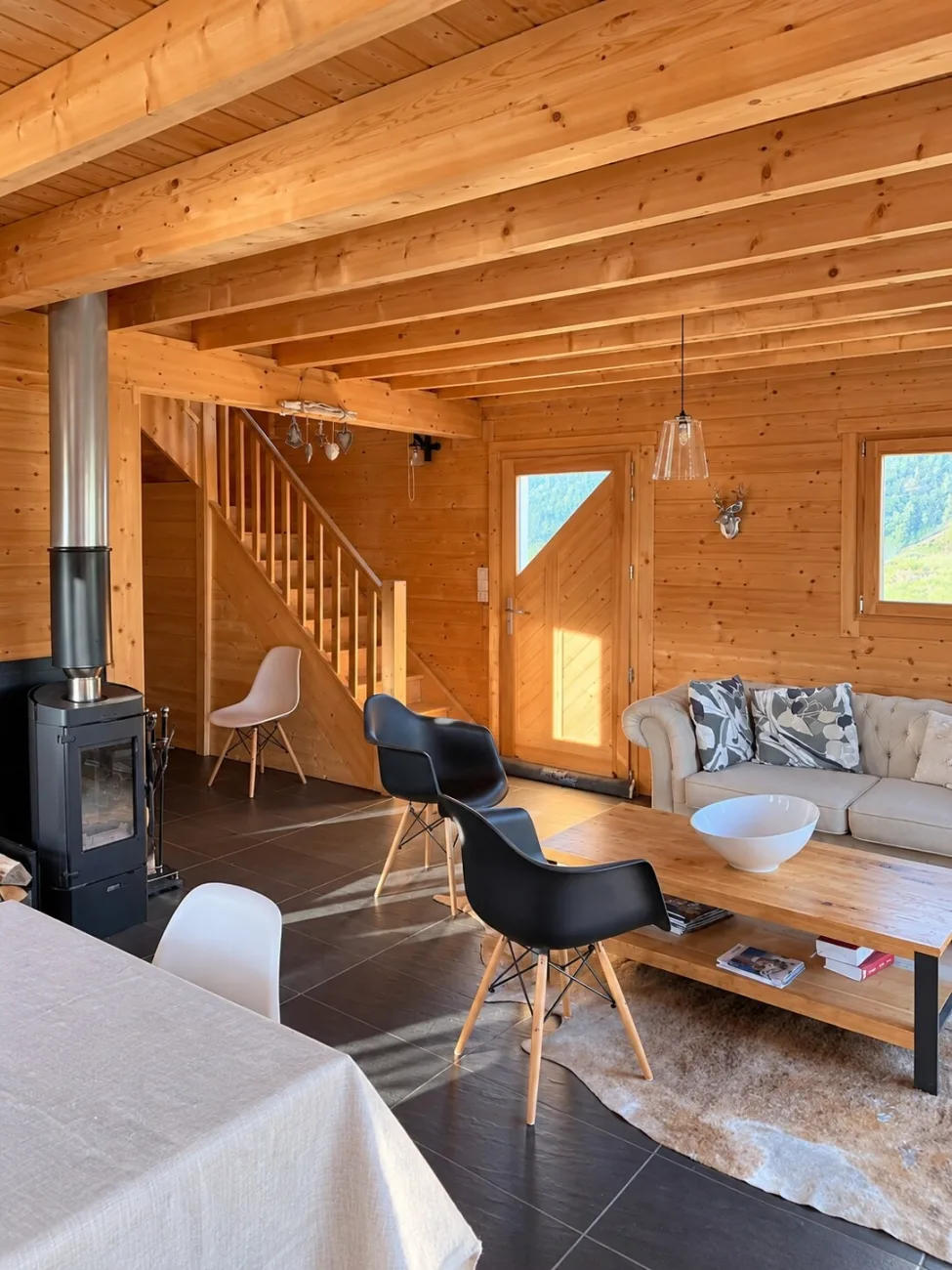 Salon lumineux avec poêle à bois et escalier vers l'étage