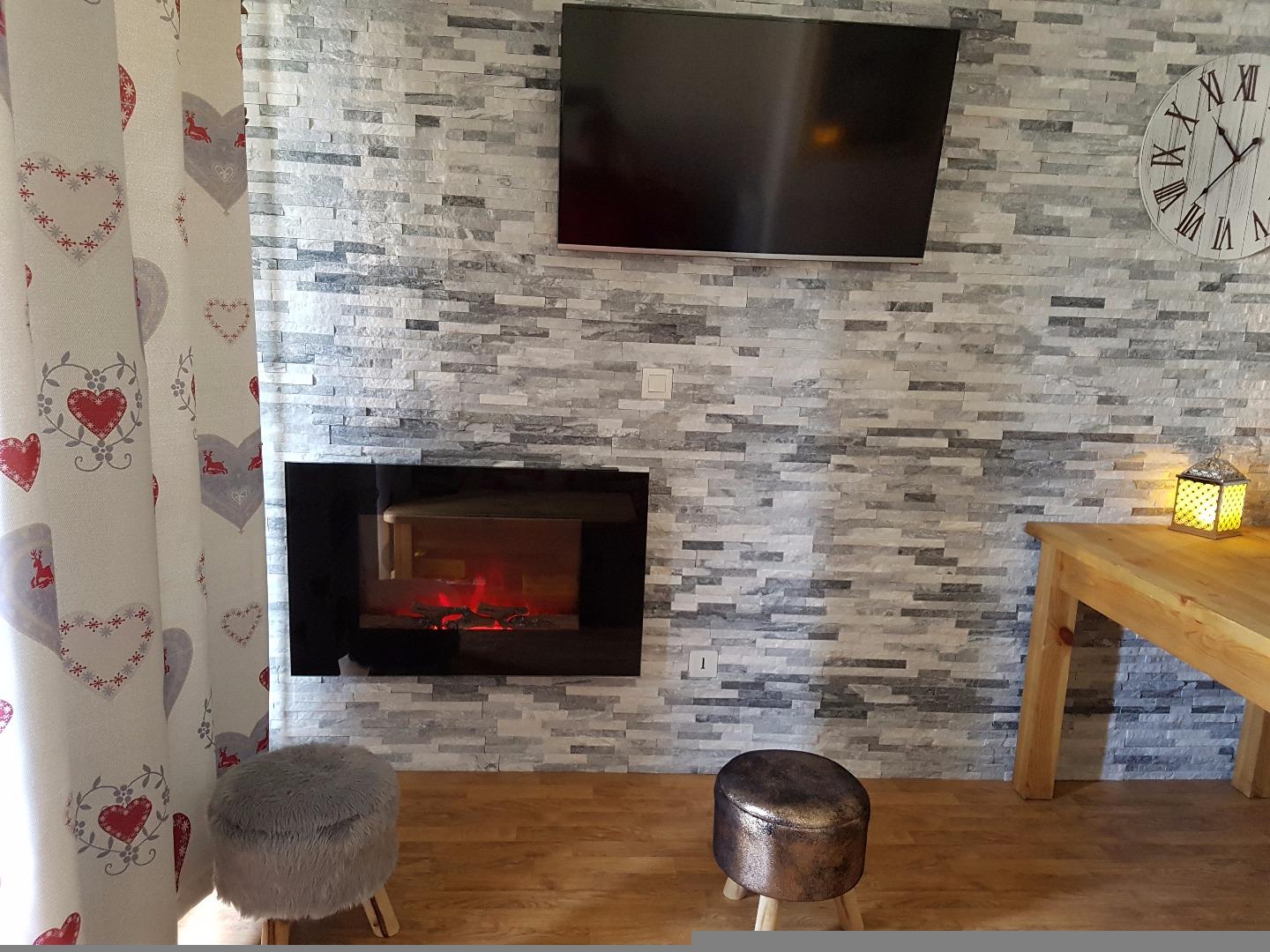 Nouvelle photo grande tv ecran plat et un radiateur immitation cheminée sur mur en pierres 