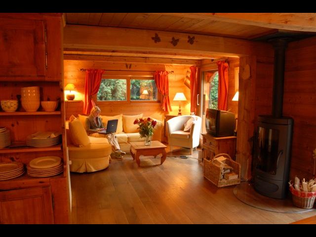 Le salon tout en bois avec vieilles poutres apparentes, et dont les baies vitrées (situées sur la droite de la photo)donnent plein sud, sur la terrasse, et face au mont-blanc