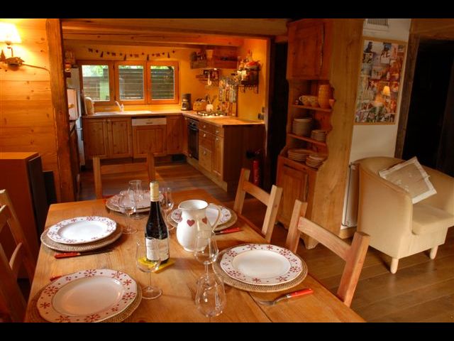 Salle à manger avec ,au fond, la cuisine; à droite de la personne qui a pris la photo, se trouve la deuxième baie vitrée donnant sur la terrasse