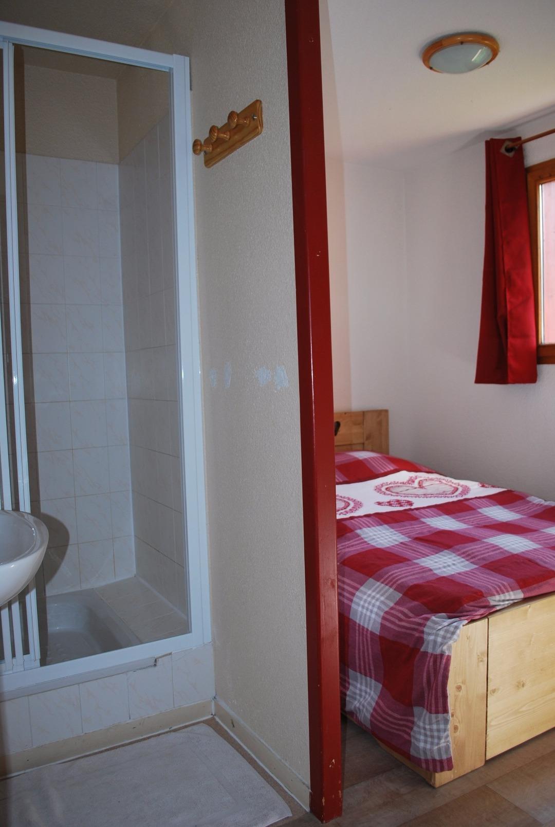 Vue de la première chambre avec sa salle d'eau (douche et lavabo)