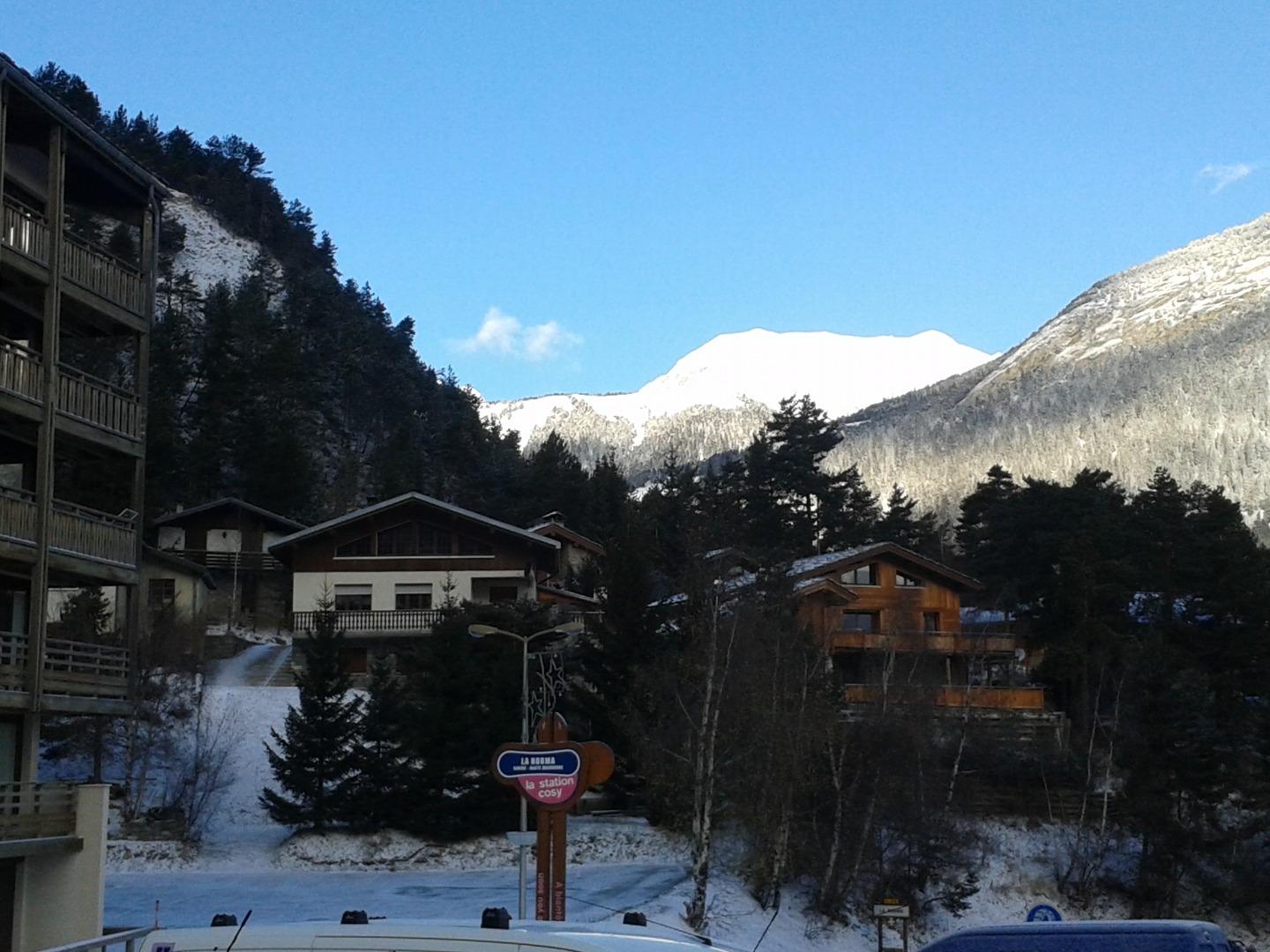 vue du balcon donnant sur un parking   ; belle vue sur les montagnes avec la neige