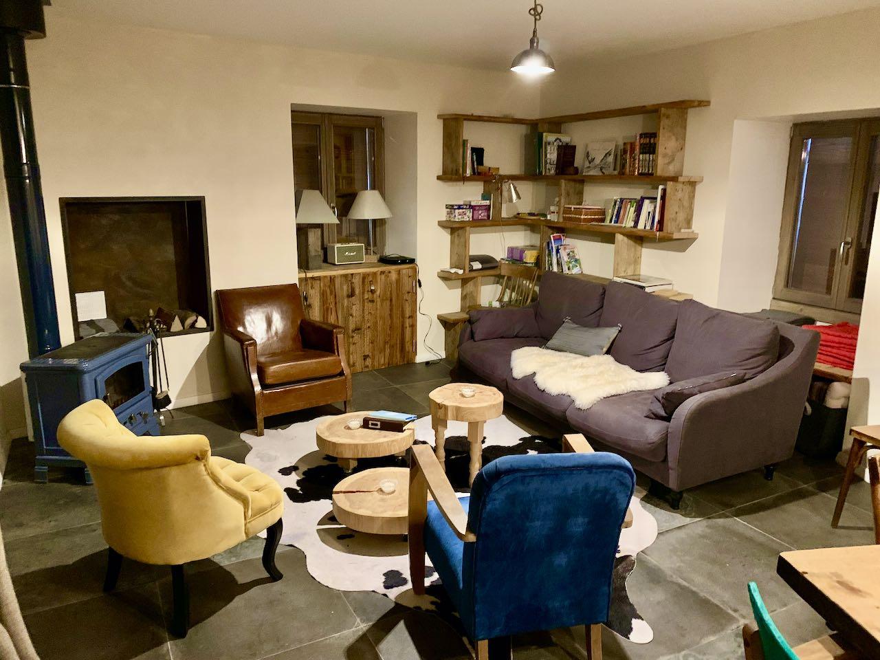 Salon avec poêle à bois, tv, console de jeux, jeux de société, bibliothèque, sofa, fauteuils, tables basses.