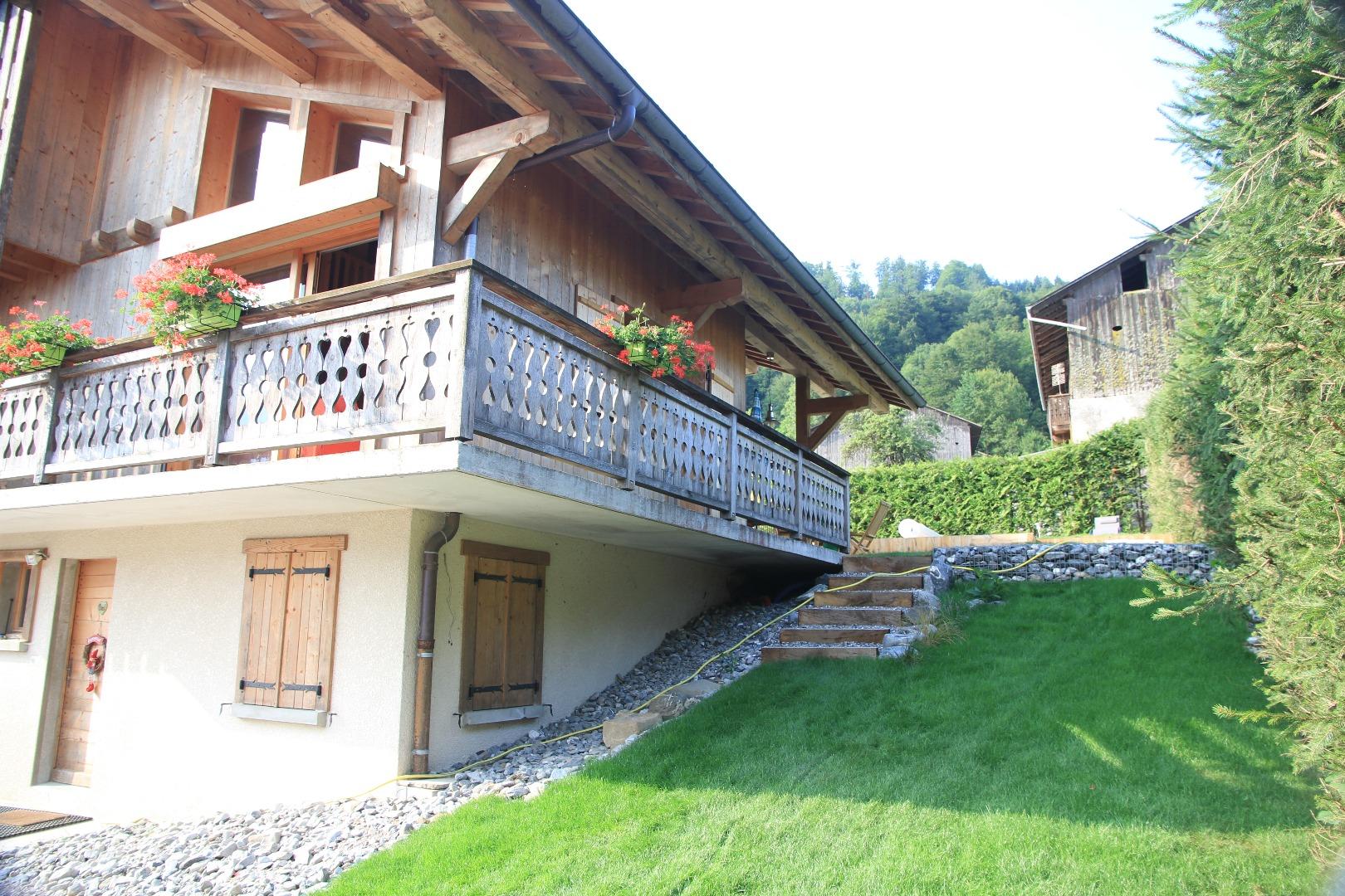 vue partielle du chalet l'été, partie latérale du jardin