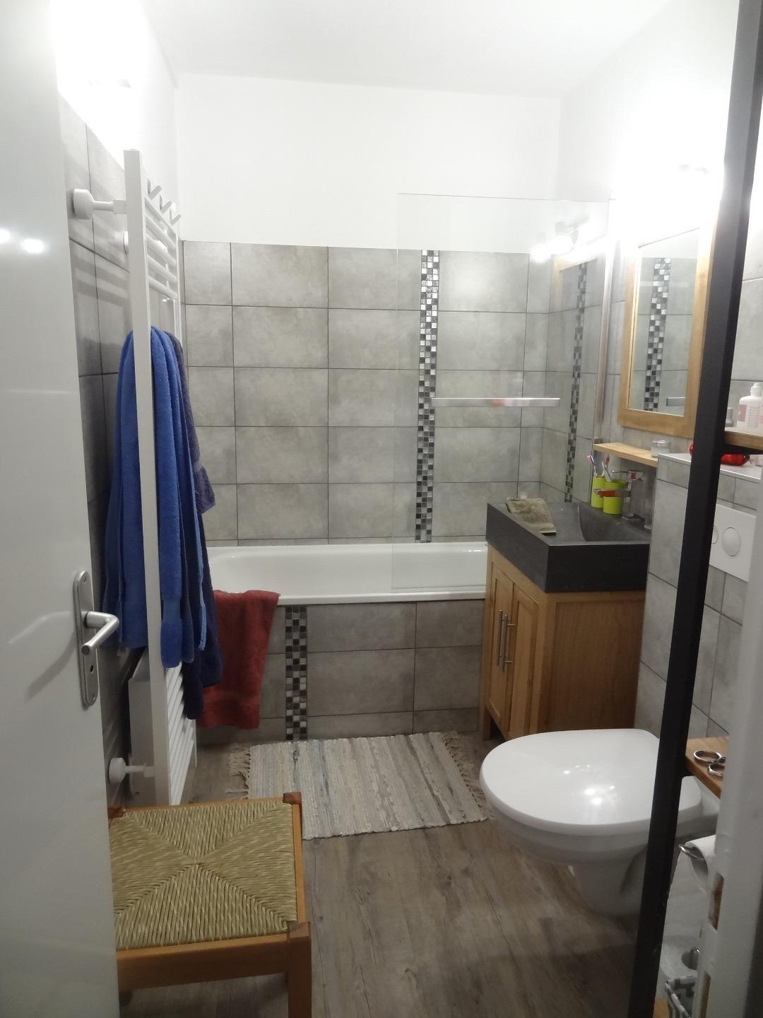 La grande salle de bain avec baignoire, WC, lavabo et radiateur sèche serviettes