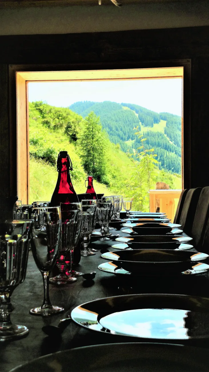 Repas montagnard  : table de salle à manger pour 19 convives prête pour une raclette face au panorama de la montagne

