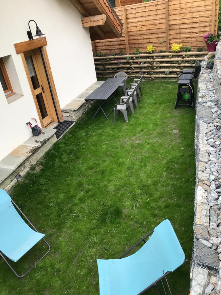 Jardin à l'arrière du chalet au niveau de la pièce à vivre avec Barbecue WEBER et chaises longues