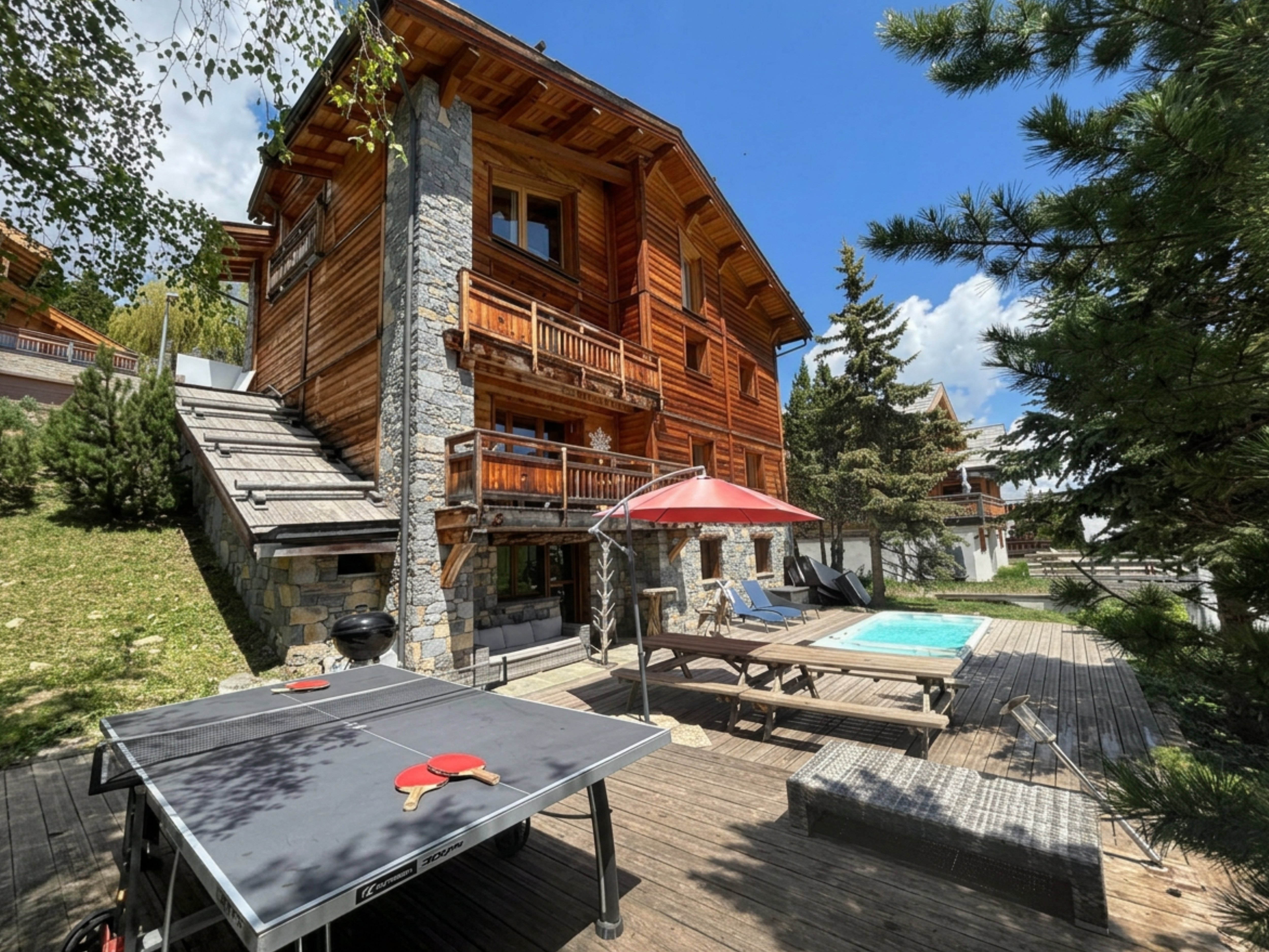 Ambiance d'été au chalet : profitez d'une partie de ping-pong sur la terrasse ensoleillée, entre deux plongeons dans le spa de nage chauffé.