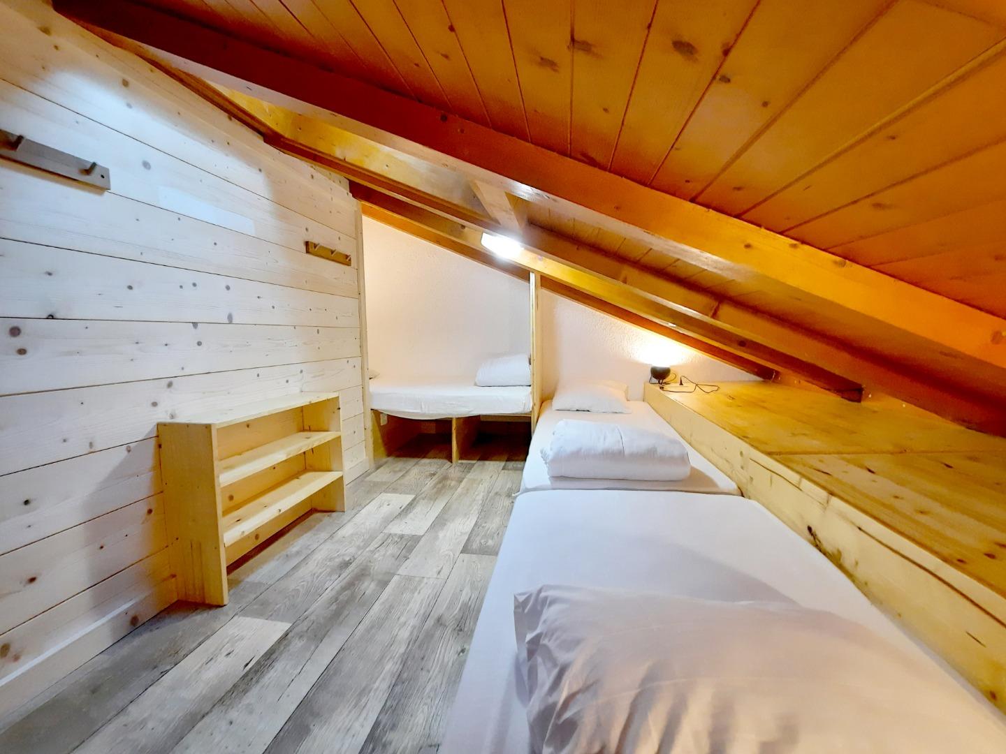 En mezzanine mansardée, chambre n°1 avec 3 lits simples (90x190 et 2x 80x190cm), velux avec occultant. Nombreux rangements, 2 prises 230V par lit.