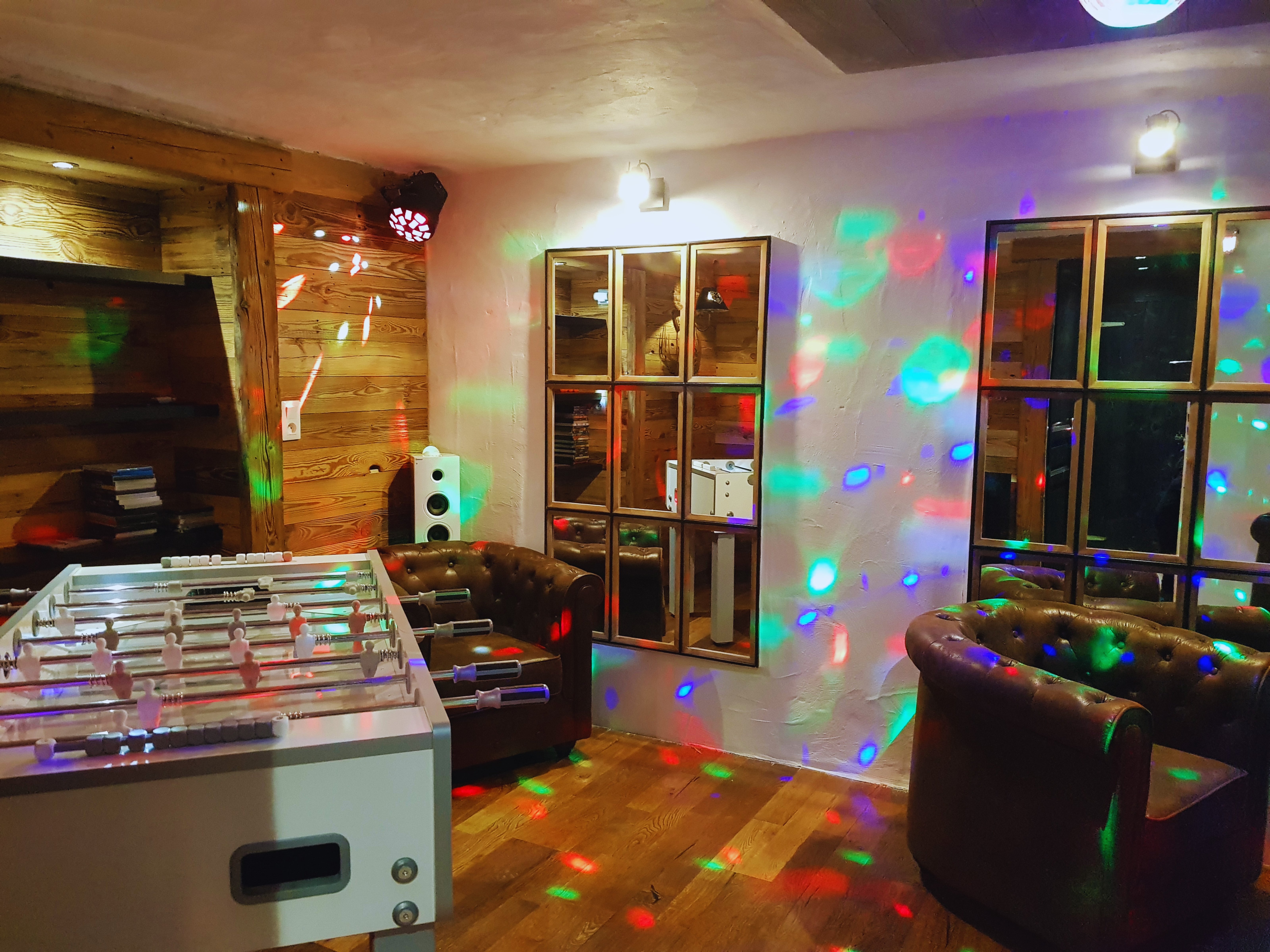 Notre espace festif au rez-de-chaussée : baby-foot et piste de danse privée pour prolonger vos soirées en chalet.