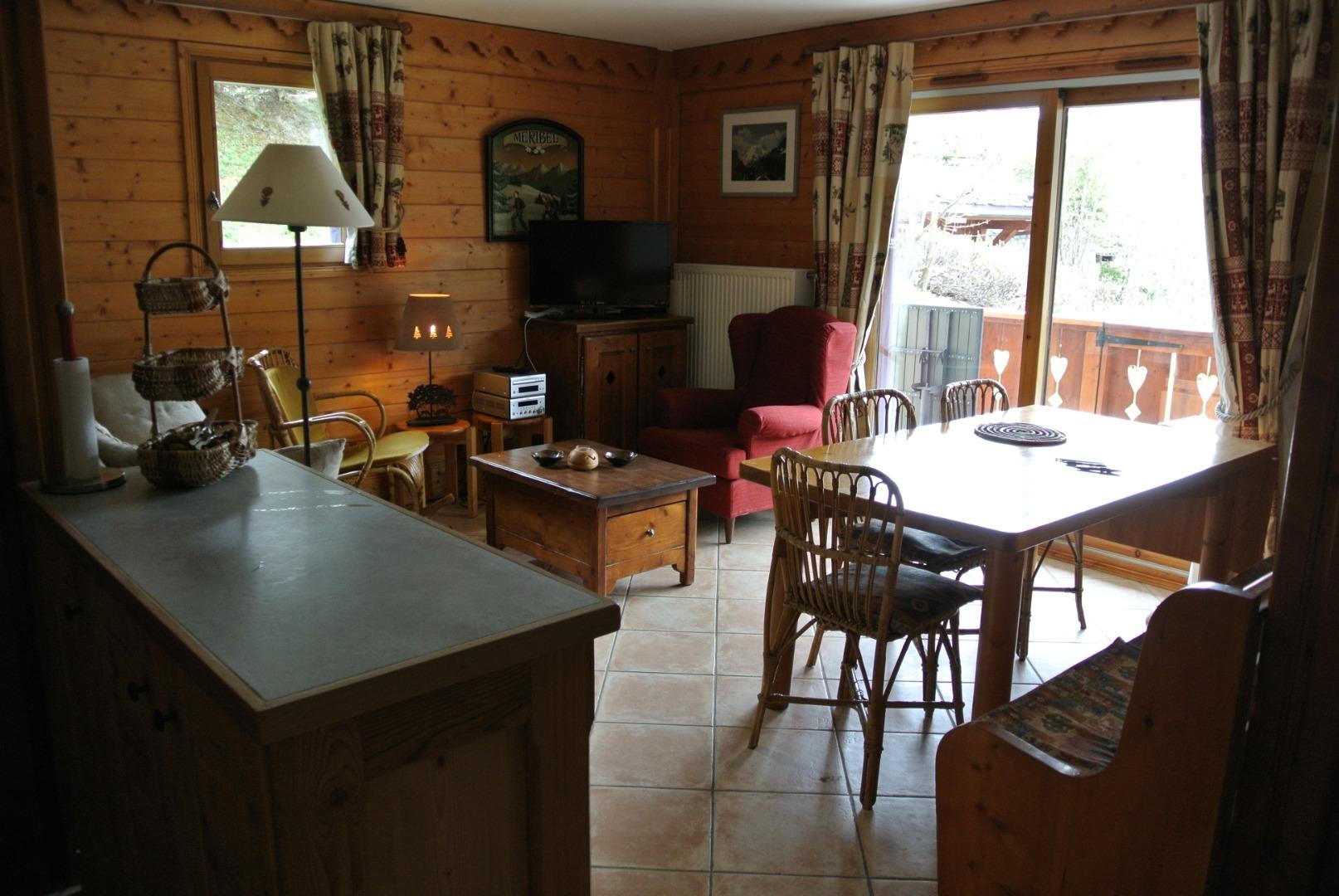 Pièce de vie vue de l'entrée de l'appartement.
A droite table banc et chaises du coin repas très confortable et spacieux
a gauche meuble plan de travail séparant le coin cuisine du séjour . Meuble accueillant une partie de la vaisselle
Baie vitrée  des